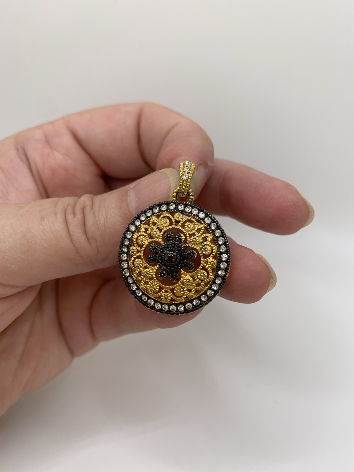 Round gold tone filigree pendant/ black quatrefoil motif & a halo of clear stone