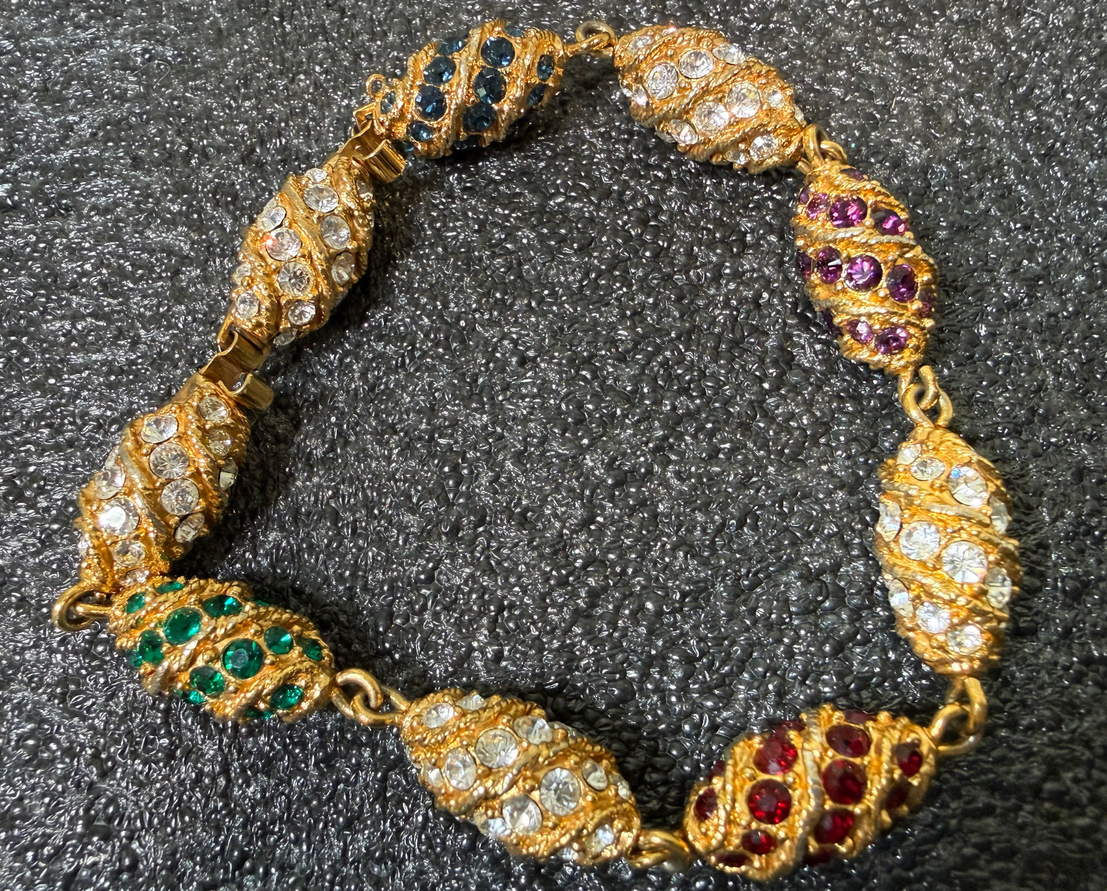 Gold tone bracelet egg shaped red, green blue, clear stones