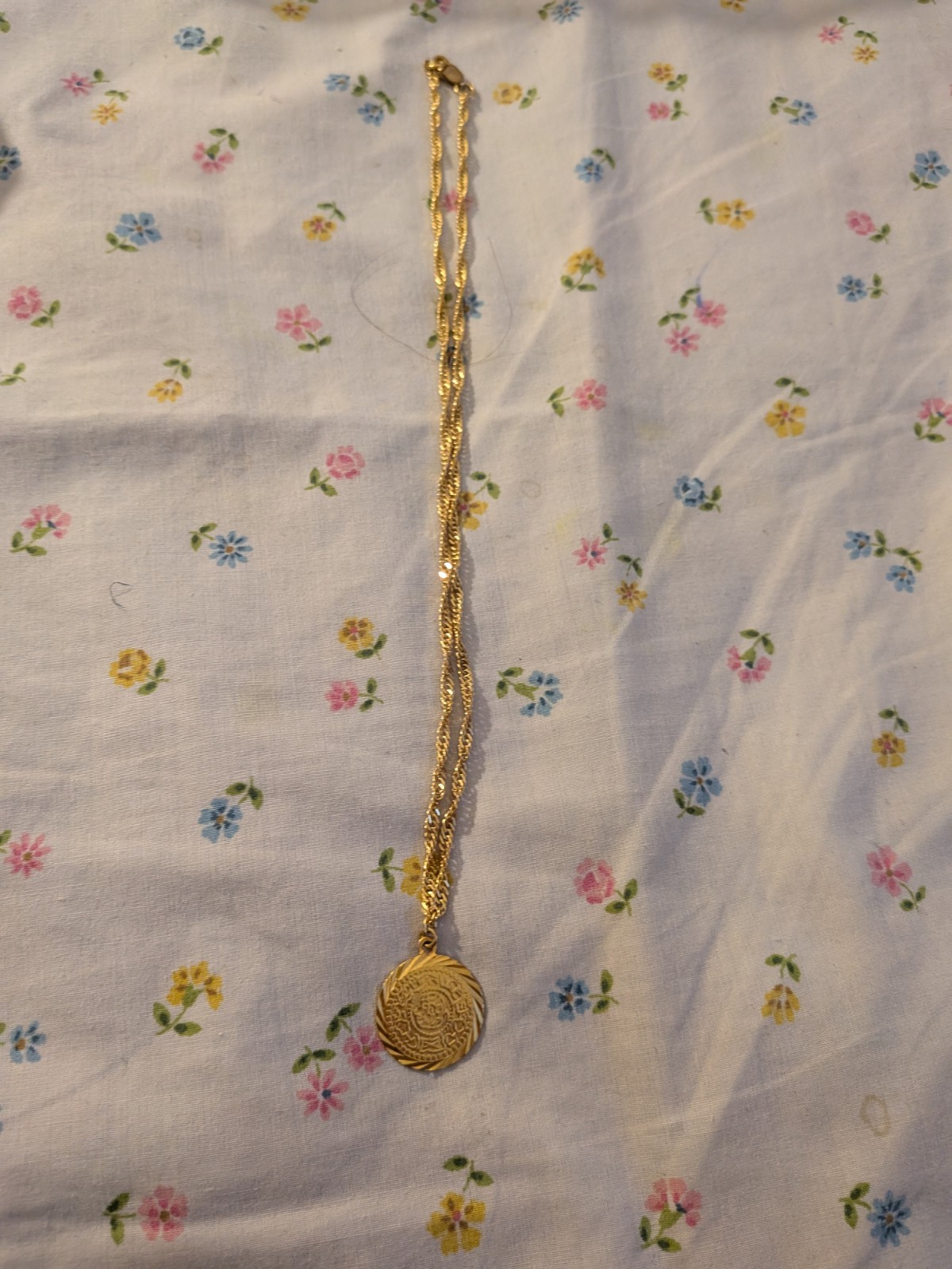 This gold-toned necklace- circular medallion pendant – delicate rope chain.