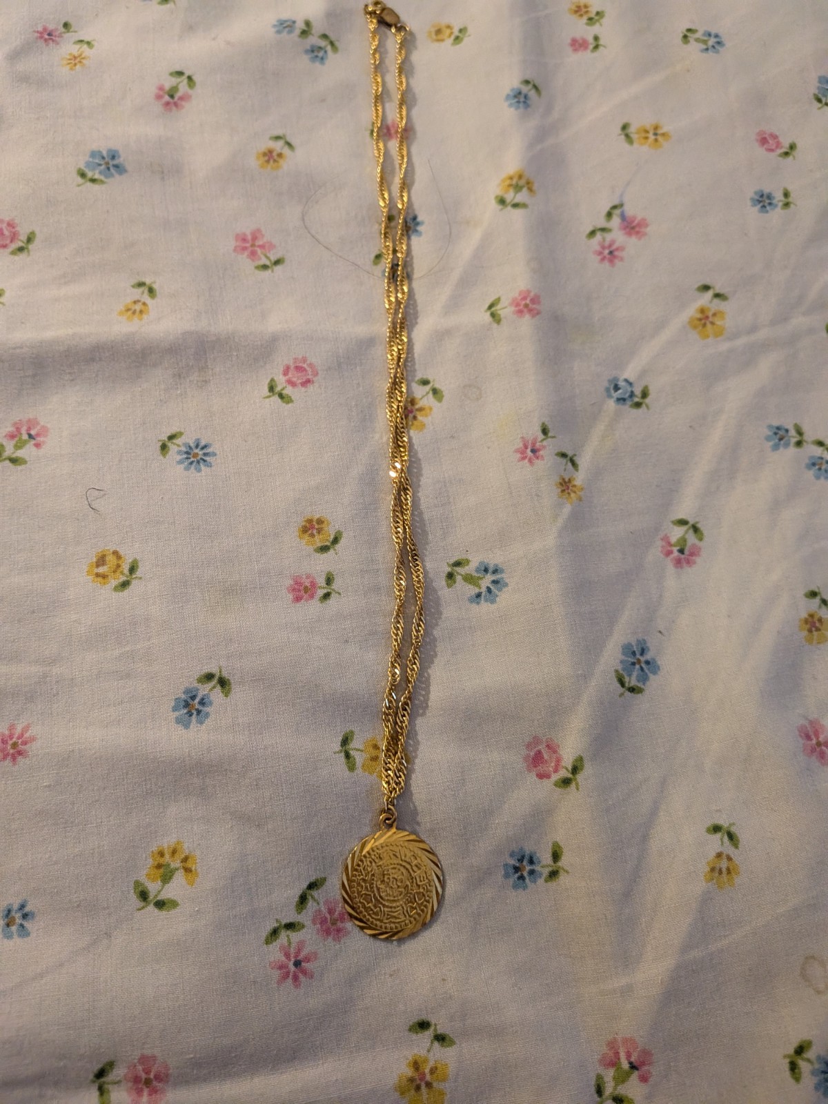 This gold-toned necklace- circular medallion pendant – delicate rope chain.