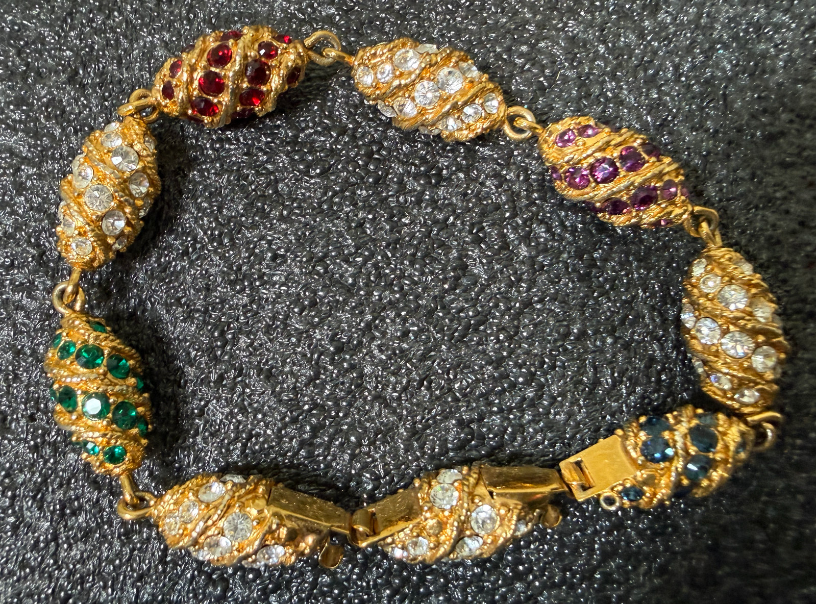 Gold tone bracelet egg shaped red, green blue, clear stones
