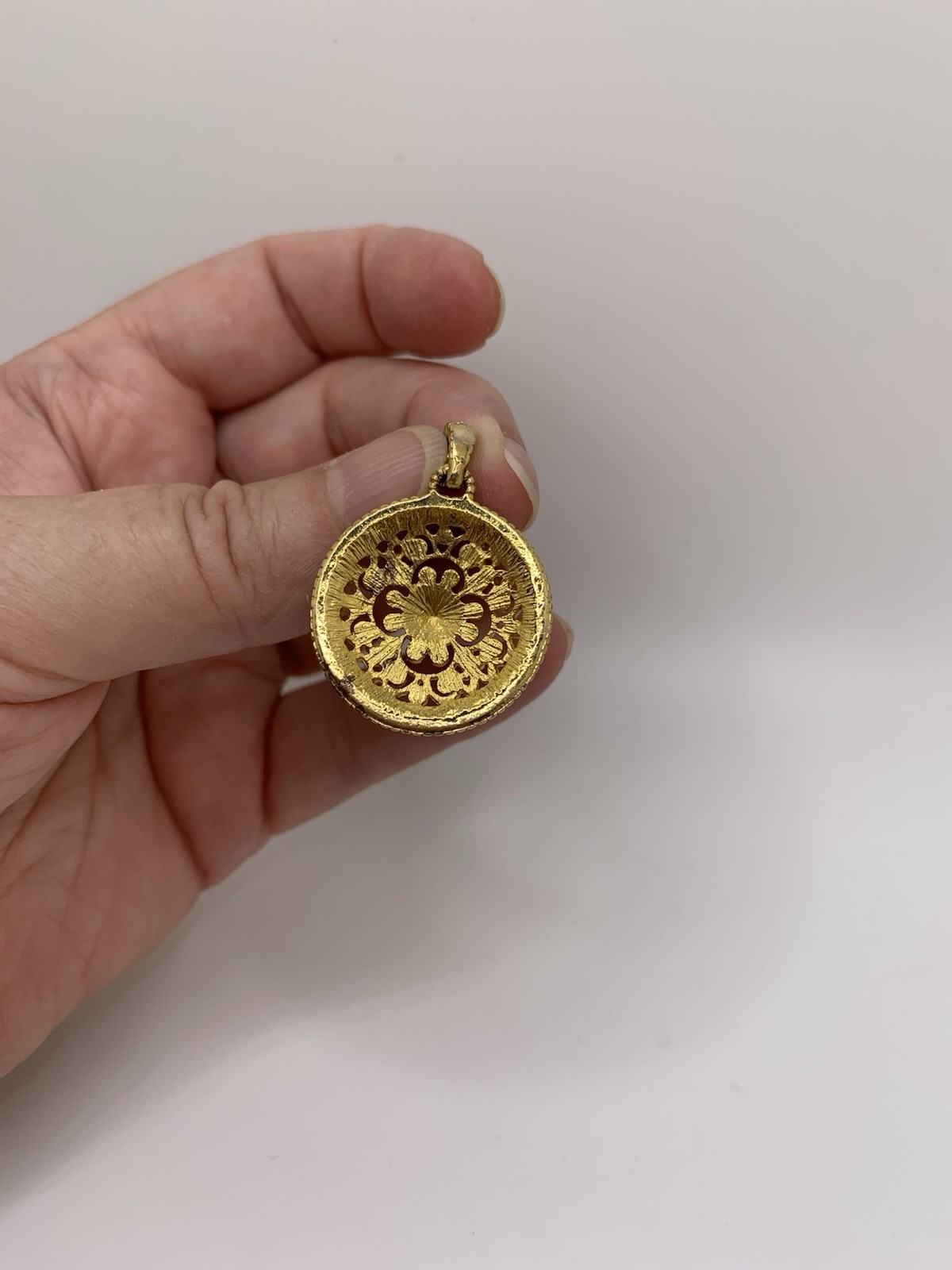Round gold tone filigree pendant/ black quatrefoil motif & a halo of clear stone