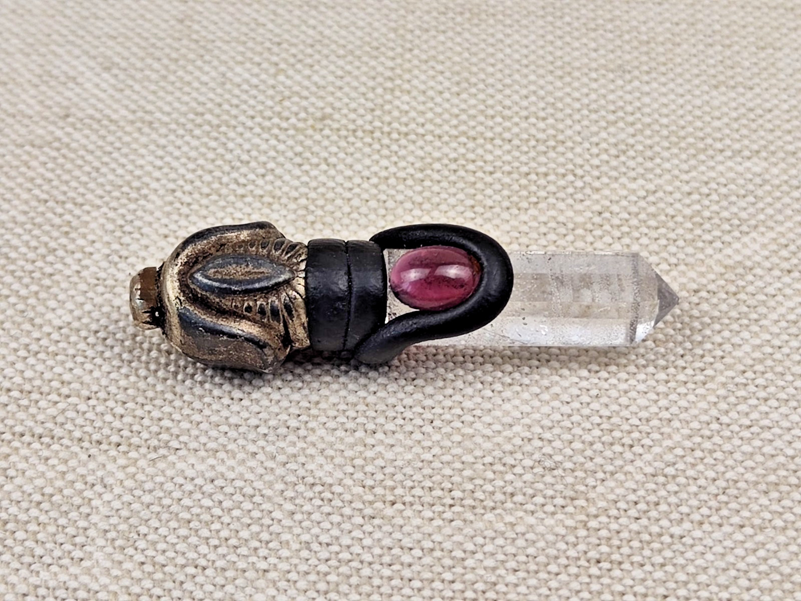 A pendant or talisman made of rock crystal and accented with a rose-red stone