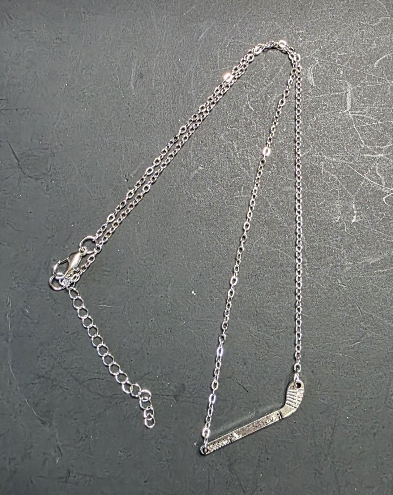 Silver Toned Hockey Stick necklace. 18″ w/ 2.5″ extender