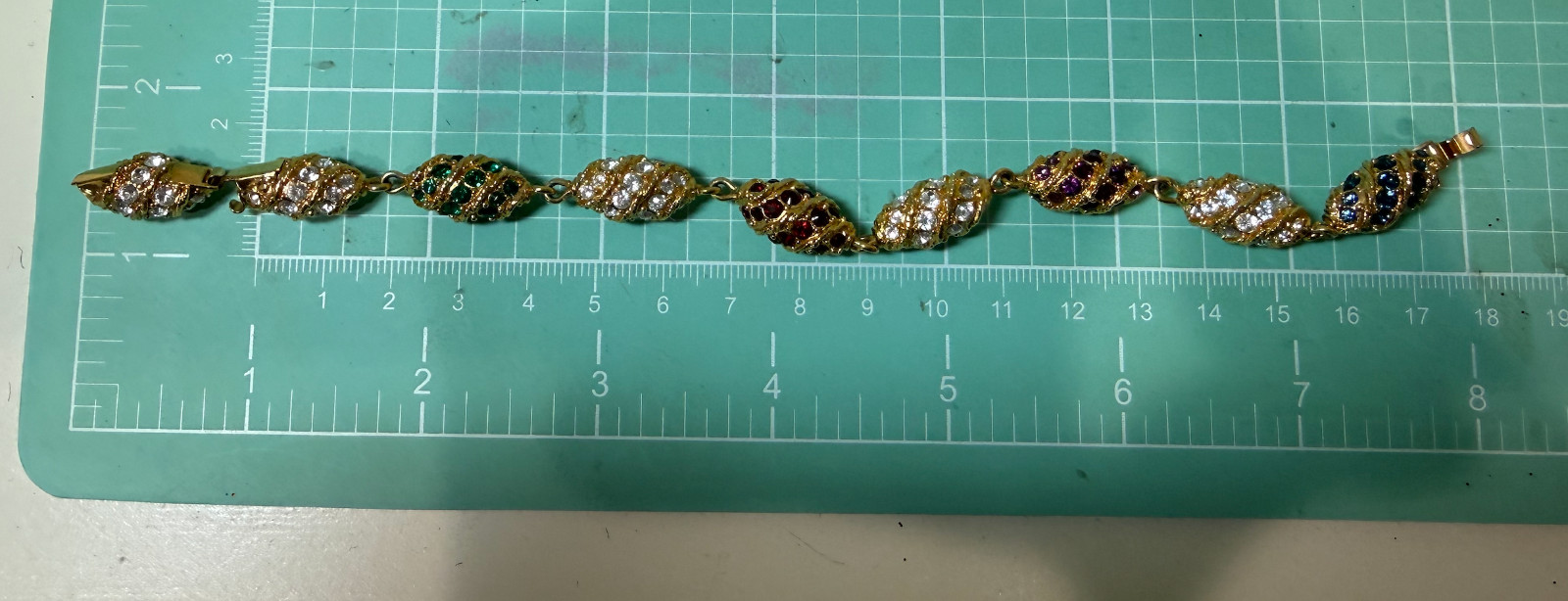 Gold tone bracelet egg shaped red, green blue, clear stones