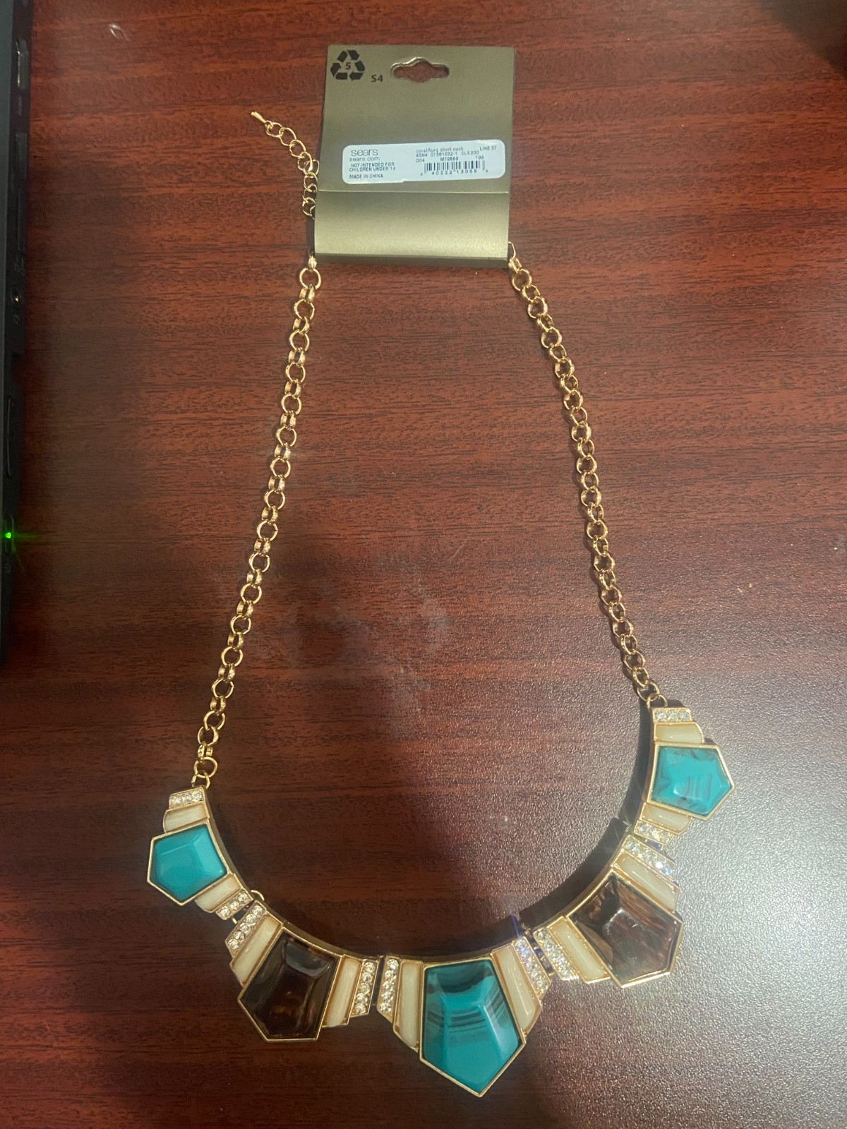 Gold chained necklace with cyan, white and oak brown gemstones.