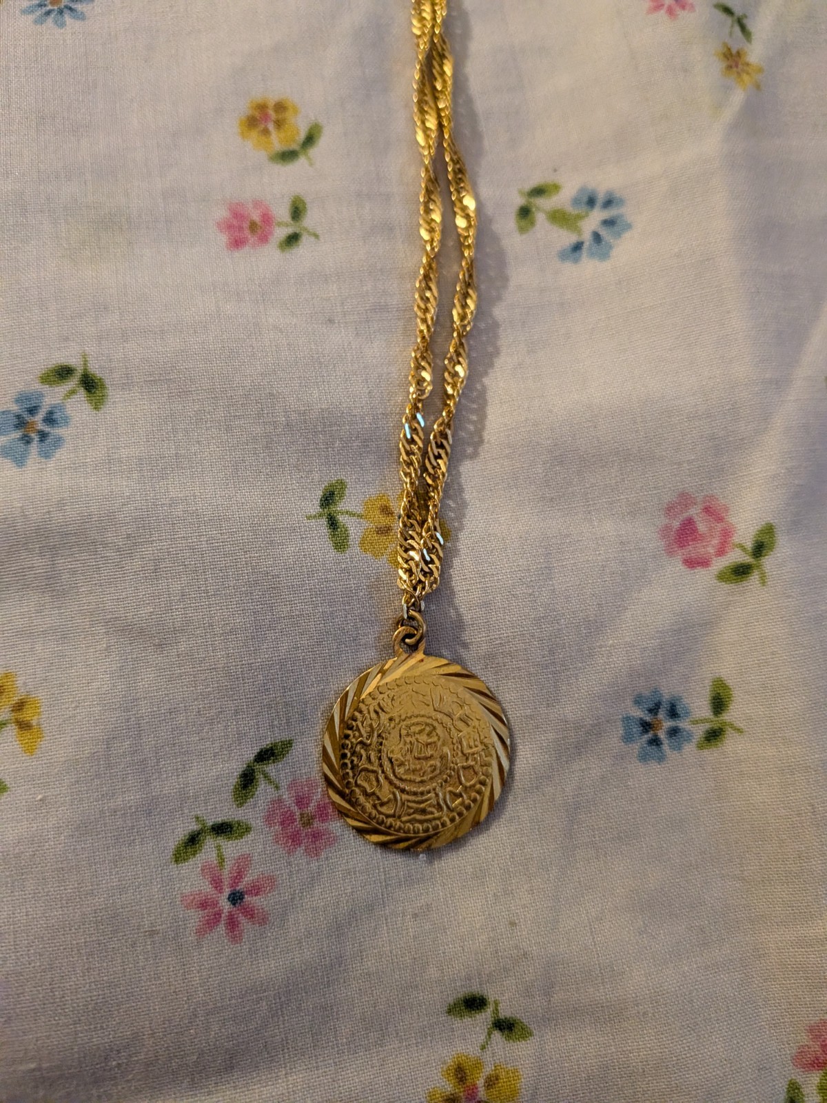 This gold-toned necklace- circular medallion pendant – delicate rope chain.